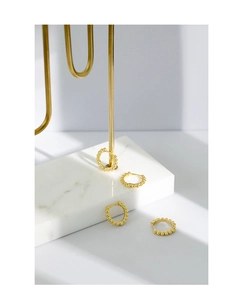 Detailed view of four gold beaded hoop earrings displayed on a marble jewelry stand