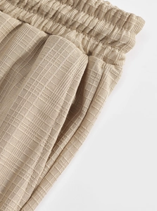 Détail de la taille élastique et poche latérale du pantalon cargo en maille beige