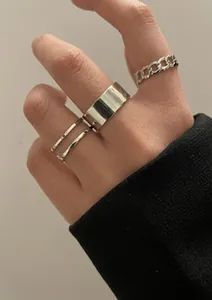 Détail d'un ensemble de quatre bagues argentées au design minimaliste lisse et tressé