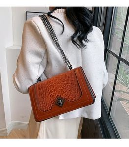 Detail of red-brown crocodile texture and dark metal chain strap on a vintage bag