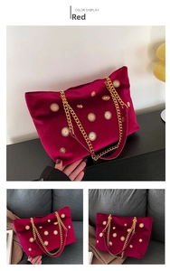Detail of red velvet tote bag featuring golden sunflower rivets and dual chain straps