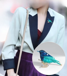 Detail of a bird brooch with blue and green enamel and rhinestones on a blazer