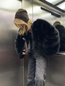 Chic faux fur jacket with wide cuffs paired with grey rhinestone jeans and a beanie