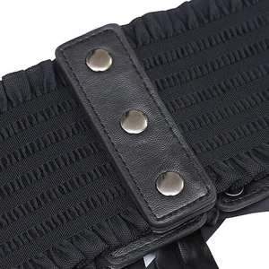 Detail of black wide elastic waist belt featuring PU leather front and metal rivet accents