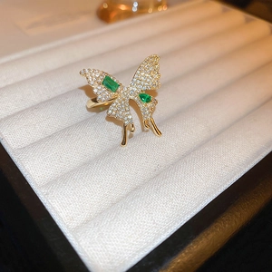 Detailed macro shot of a gold butterfly ring with emerald accents on white velvet
