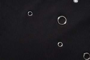 Close-up of black ribbed fabric featuring polished silver metal eyelet hardware details