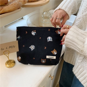 Handheld black canvas pouch with cute cat embroidery in a cozy cafe setting