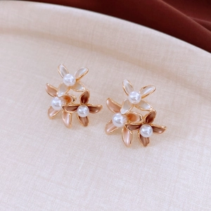 Macro detail of 18K gold-plated floral earrings with white pearls and enamel petals