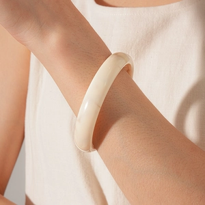 Close-up of minimalist creamy white resin bangle showing smooth texture and stone patterns