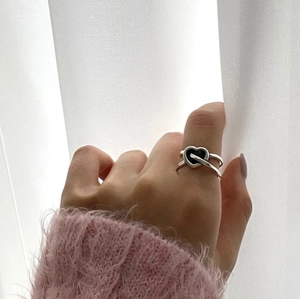 S925 sterling silver heart ring with black center on hand against white backdrop
