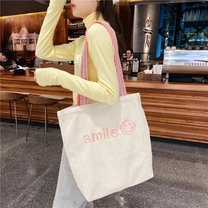 White canvas tote bag with pink smile embroidery and patterned jacquard strap