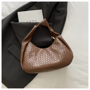 Detail of brown woven leather handbag featuring a unique single knotted handle design