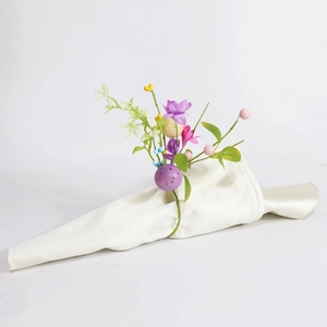 Close-up of Easter napkin ring with purple faux flowers and colorful speckled eggs