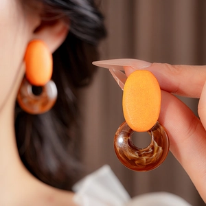 Detail view of retro geometric resin earrings in orange and brown marble texture