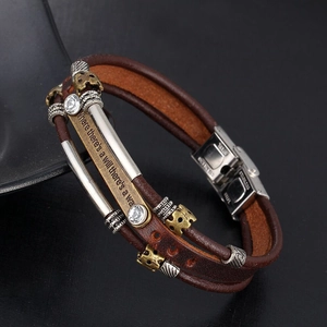 Détail d'un bracelet en cuir tressé avec barres métalliques et gravure inspirante