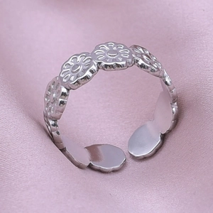Macro shot of silver adjustable flower ring on pink silk fabric detail view