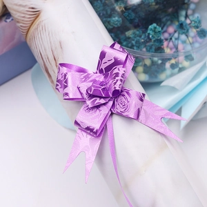 Close-up of a purple gift ribbon bow with elegant rose patterns on a white package