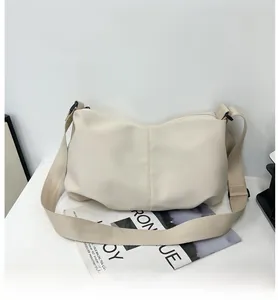 Detail of off-white dumpling bag showing soft leather texture and wide fabric strap