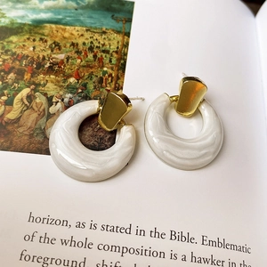 Detail shot of hollow circle earrings with gold metal top and white textured finish