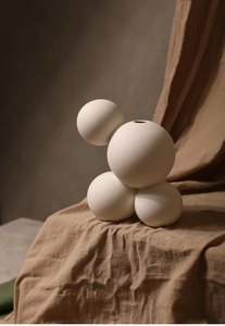 Detail einer minimalistischen weißen Keramikvase mit vier verbundenen matten Kugeln
