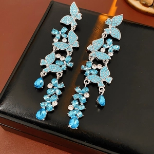 Detail of silver long tassel earrings featuring light blue butterfly and rhinestone accents