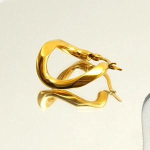 Macro shot of gold twisted geometric hoop earrings with a reflective metallic finish