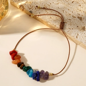 Bracciale chakra fatto a mano con pietre naturali e corda intrecciata su pietra beige