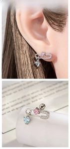 Detail of safety pin earring with pink star gemstone and blue heart-shaped pendant