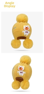 Detail of yellow knit baby hat featuring plush pom-poms and a cute cartoon bear patch