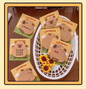 Close-up of cute cartoon Capybara sticky notes featuring warm brown tones on wood desk