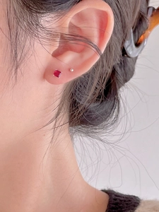 Close-up of square red zircon stud earrings on ear for a minimalist jewelry style