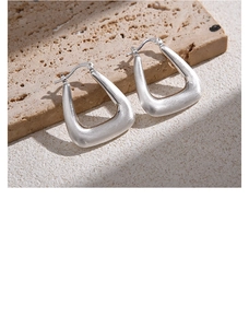 Macro shot of silver brushed metal U-shaped earrings on textured stone surface