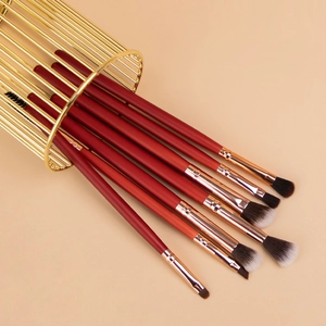 7-piece burgundy professional eye makeup brush set with gold metal holder on beige background