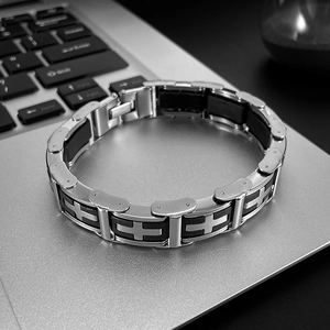 Classic silver titanium steel cross bracelet for men resting on a metallic laptop surface