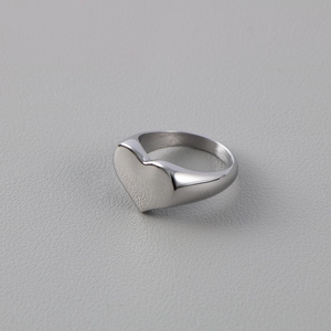 Macro view of a silver heart-shaped signet ring with a polished mirror finish surface