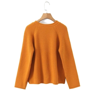 Pull en grosse maille jaune moutarde à col rond et manches raglan sur un cintre en bois