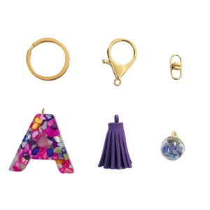 Detailed view of resin letter A keychain with purple tassel and gold hardware on white