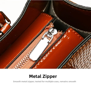Detailed close-up of smooth silver metal zipper on caramel brown crocodile embossed handbag