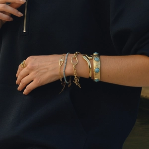 Detail of layered 18K gold stainless steel bracelets with turquoise and evil eye stones
