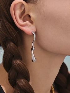 Gros plan de boucles d'oreilles géométriques argentées au design métallique ondulé