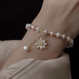 Elegant freshwater pearl bracelet with zircon flower charm on model's wrist