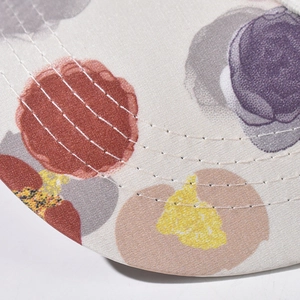 Detailed macro view of embroidered seams on a colorful polka dot patterned baseball cap