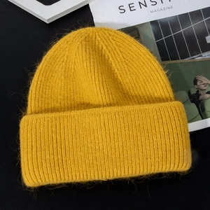 Detailed texture of thick ginger yellow plush rabbit fur knit hat for winter warmth