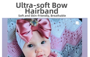 Macro view of a soft pink satin bow baby headband with crystal decor and flexible band