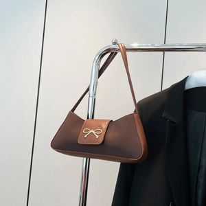 Brown matte leather baguette bag with a gold bow buckle shown on a metal hanger
