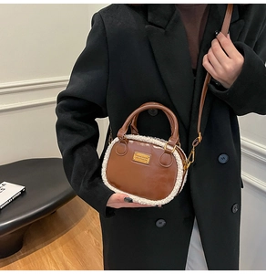 Detail of plush shearling and dark brown leather crossbody bag with metal plaque