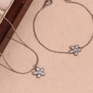 Macro detail of silver flower pendant necklace and matching bracelet on elegant surface