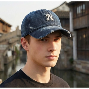 Detail of vintage denim baseball cap with white N letter patch and frayed edges