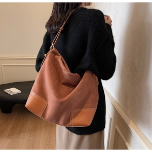 Detailed view of brown suede tote bag featuring distinctive leather patchwork and white stitching