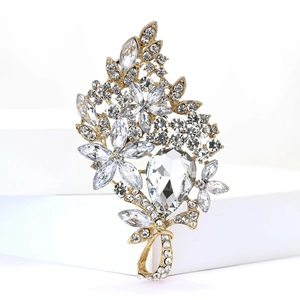 Macro view of a gold flower brooch featuring clear faceted crystals and leaf designs